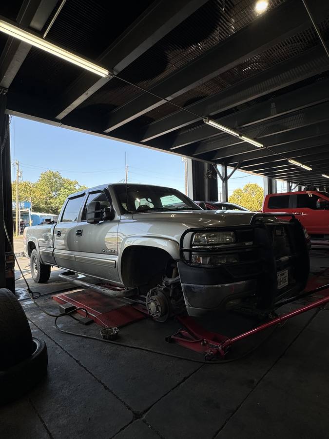 A pickup on the rack inside the bay with a wheel removed and the brake rotor exposed.